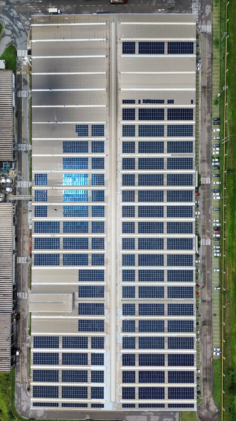 Usina solar sobre telhado industrial branco corrugado, painéis fotovoltaicos em cobertura comercial