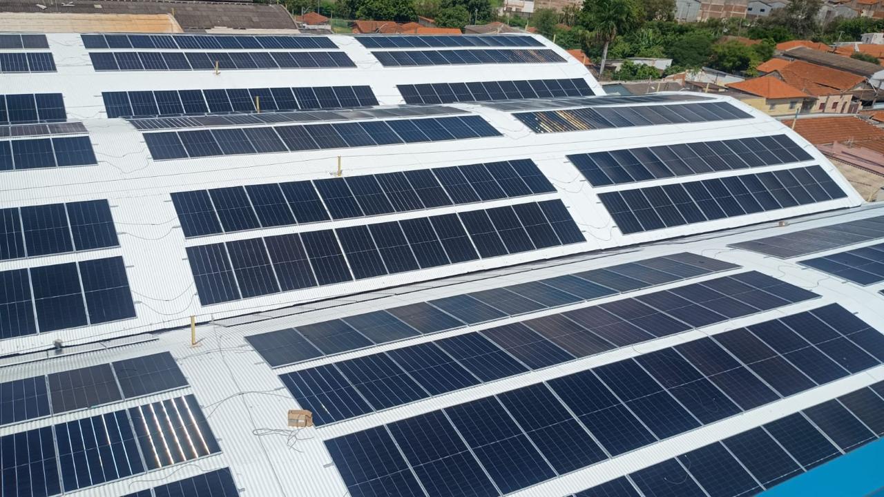 Usina solar de grande porte em galpões industriais, vista aérea com telhados cobertos por painéis fotovoltaicos