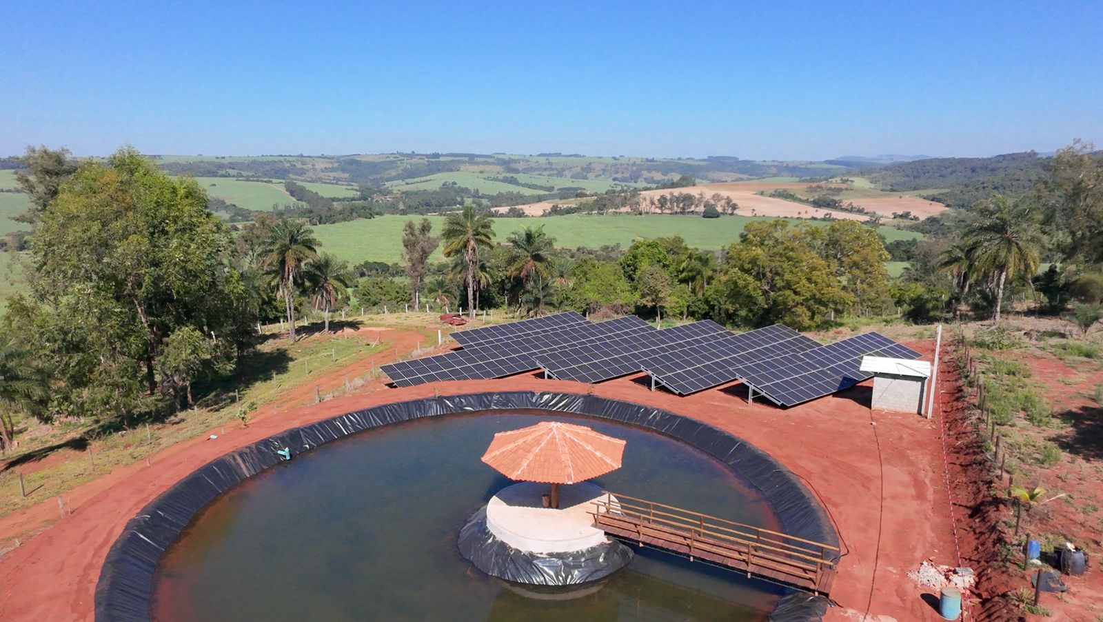Sistema de energia solar em propriedade rural com painéis fotovoltaicos ao lado de reservatório, fazenda sustentável