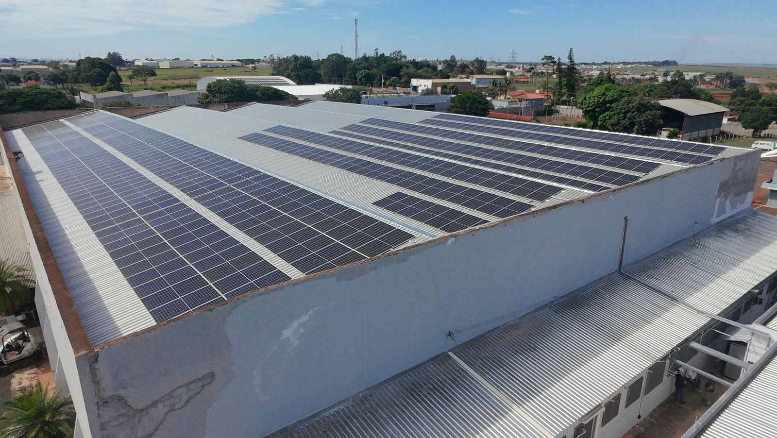 Galpão industrial com painéis fotovoltaicos instalados no telhado, projeto solar comercial vista aérea